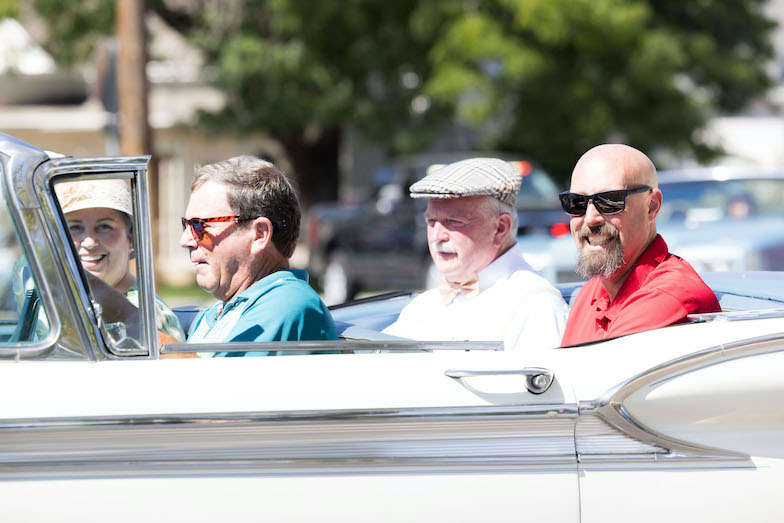 An elderly woman, two elderly men, and a middle-aged man in a vintage convertible car